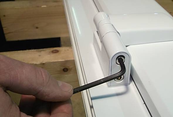 White Patriot Plus flag hinge fitted to a profile, with a hex key at the compression adjustment.